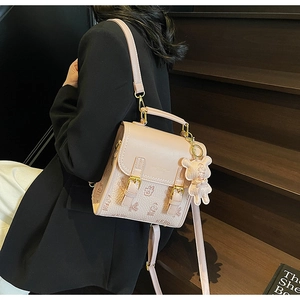 Detail des rosa Mini-Rucksacks mit Bärenmuster, zwei Schnallen und niedlichem Anhänger