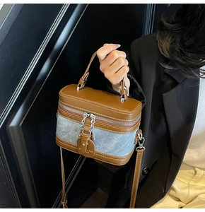 Detail of retro box bag featuring brown leather and light blue denim patchwork