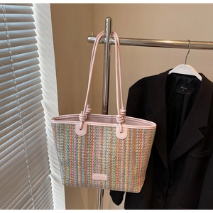 Detail of colorful striped woven tote bag with pink leather trim hanging on a rack