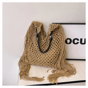 Detail of woven beach tote showing hollow mesh pattern, long side tassels, and black leather strap