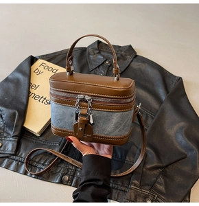 Detail of vintage denim and leather crossbody box bag with silver zippers and chain