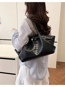 Fashionable black crocodile texture wing bag with gold hardware shown on a model