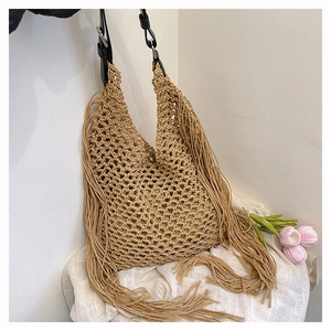 Close-up of khaki hollow-out woven tote bag with long fringes and black leather strap