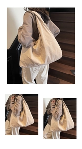 Detail of a large minimalist beige nylon tote bag worn as a shoulder bag in a cozy setting