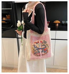 Detail of pink knitted tote bag with traditional Chinese dragon embroidery and geometric pattern