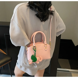 Detail of pink lychee leather bucket bag with elephant charm on grey knit background