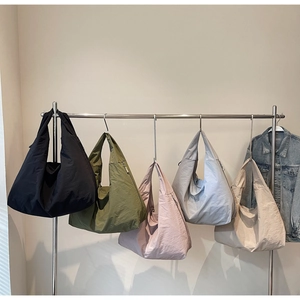 Five nylon hobo bags in assorted colors hanging on a metal rack for store display