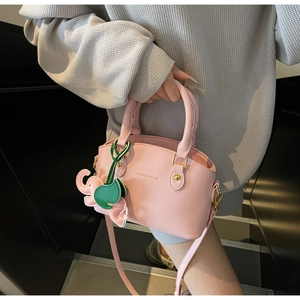 Detail of pink lychee leather handbag with elephant charm and gold fashion branding