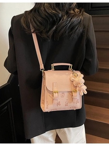 Modische rosa Umhängetasche mit Bärenanhänger an einem Model in einem Innenraum