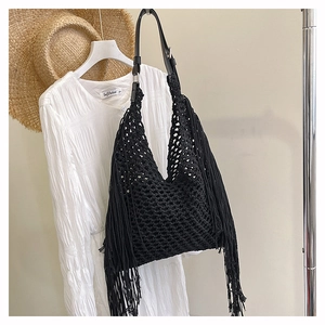 Detail of black crochet tote bag with long fringes and leather strap in beach style