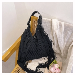 Close-up of black handmade crochet tote bag with long bohemian tassels and leather strap