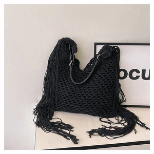 Detail of hand-woven black beach bag with long fringes and leather shoulder strap