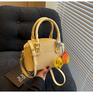 Detail of yellow lychee leather handbag with cute elephant charm on a sofa