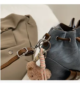 Detail der blauen Denim-Beuteltasche mit braunem Lederbesatz und silberner Metallschnalle