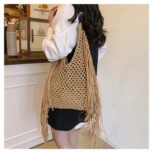 Close-up of handmade woven tote bag with long bohemian tassels and adjustable leather strap