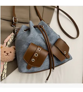 Detail der Jeans-Beuteltasche mit braunen Taschen und Plüschbär-Anhänger