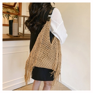 Detail of bohemian hollow woven tote bag with long tassels and black leather strap