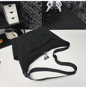 Detail of black waterproof nylon messenger bag featuring utility pockets and zip pulls