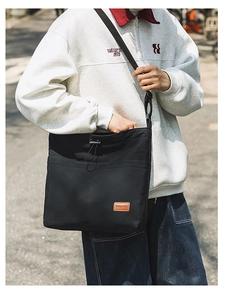 Detailaufnahme der schwarzen Nylon-Tasche mit Kordelzug und Logo-Patch aus braunem Leder