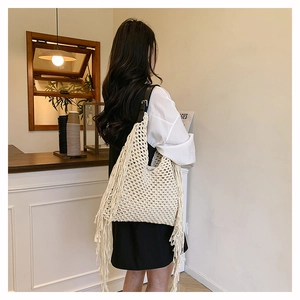 Detail of hand-woven off-white tote bag with long side tassels and black leather strap