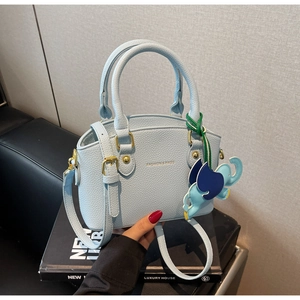 Close-up of light blue litchi pattern shell bag with a cute elephant charm