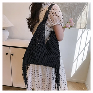 Detail of black hollow hand-woven tote bag featuring long decorative side tassels