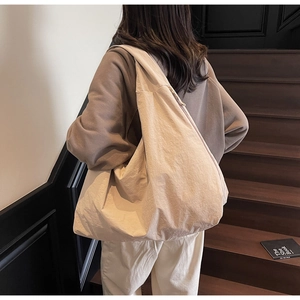 Detailed back view of a beige oversized canvas hobo bag with zip on a wooden staircase
