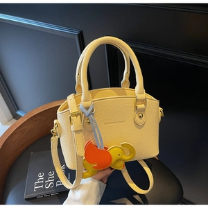 Macro detail of yellow pebble leather bucket bag featuring elephant charm and logo