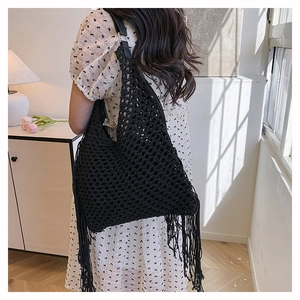 Detail of black hollow hand-woven tote bag with long tassels and bohemian style