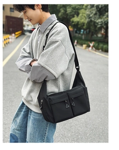 Detail of waterproof nylon crossbody bag featuring front utility pockets and triangle zippers