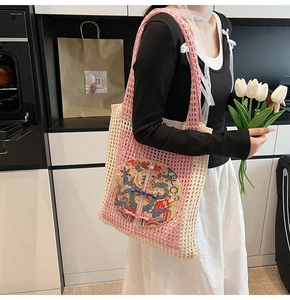 Gros plan du sac cabas au crochet rose et blanc avec broderie dragon et nœuds chinois
