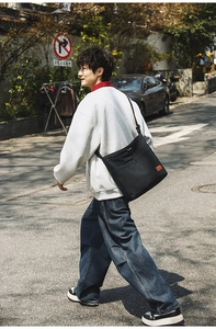 Streetstyle-Aufnahme einer schwarzen Nylon-Tasche mit Kordelzugtasche und orangefarbenem Label