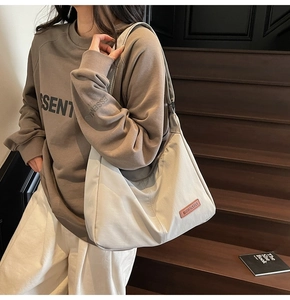 Close-up of a large grey crescent tote bag with premium leather brand patch detail