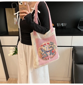 Crocheted pink and beige tote bag with intricate dragon embroidery and wide shoulder strap