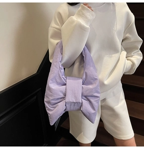 Détail du sac à bandoulière noeud en nylon violet clair porté avec une tenue blanche décontractée
