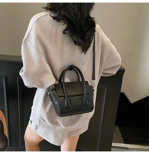 Close-up of black lychee grain leather mini square bag with cylindrical handles