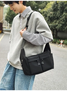 Side view of black nylon crossbody bag with dual zip pockets on male model