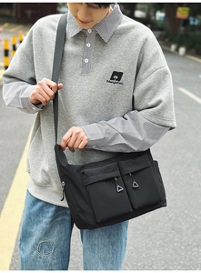 Close-up of waterproof nylon material and front pocket details of the black messenger bag