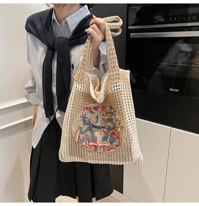 Detailed close-up of ivory woven tote bag featuring dragon embroidery and knot accents