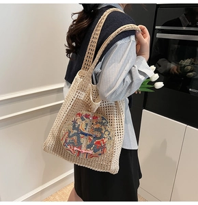 Detail of beige woven tote bag featuring dragon embroidery and traditional knots