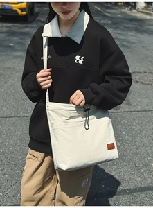 Detailansicht der cremefarbenen Nylontasche mit Kordelzug und Leder-Logo-Patch
