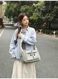 Detail of light grey nylon crossbody bag with large front pockets and wide strap