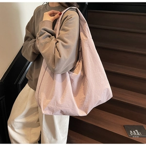 Close-up of pale pink nylon tote bag with crinkled texture fabric and wide shoulder strap