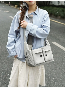 Detailed side view of a grey water-resistant nylon crossbody bag with utility pockets
