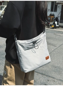 Detail der hellgrauen Nylon-Tragetasche mit Kordelzug und braunem Leder-Logo-Etikett