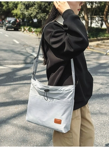 Detail der hellgrauen Nylon-Tasche mit Kordelzug und Logo-Patch aus Leder am Beutel