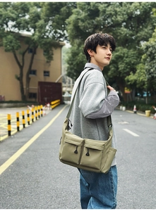 Detail of olive green nylon messenger bag with dual front zipper pockets and side pockets