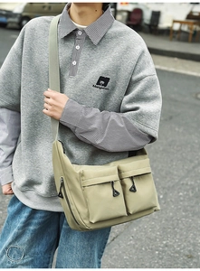 Detailed view of khaki water-resistant nylon messenger bag with dual front zipper pockets