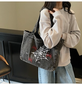 Detailansicht der grauen Denim-Einkaufstasche mit Spinnennetz-Stickerei und viel Platz