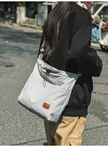 Detailansicht der hellgrauen Nylon-Tasche mit Kordelzug und breitem Schultergurt